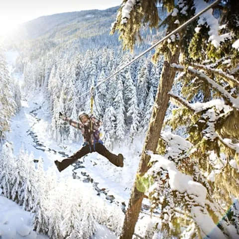 A zipliner crossing a snow-covered valley